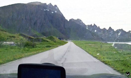 Vor uns Berge, rechts und links grüne Wiese.