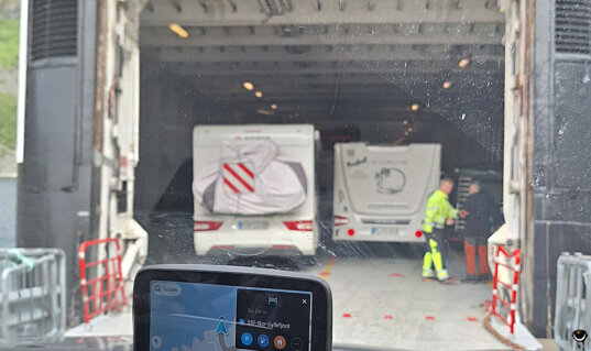Blick vom Auto in das Fahrzeugdeck der Fähre von Gryllefjord nach Andenes, auf dem bereits mehrere Wohnmobile stehen.