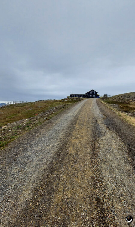 Schmale Schotterstraße führt durch eine karge Hochlandschaft hinauf zum Hotel Gildetun auf einem Bergrücken.
